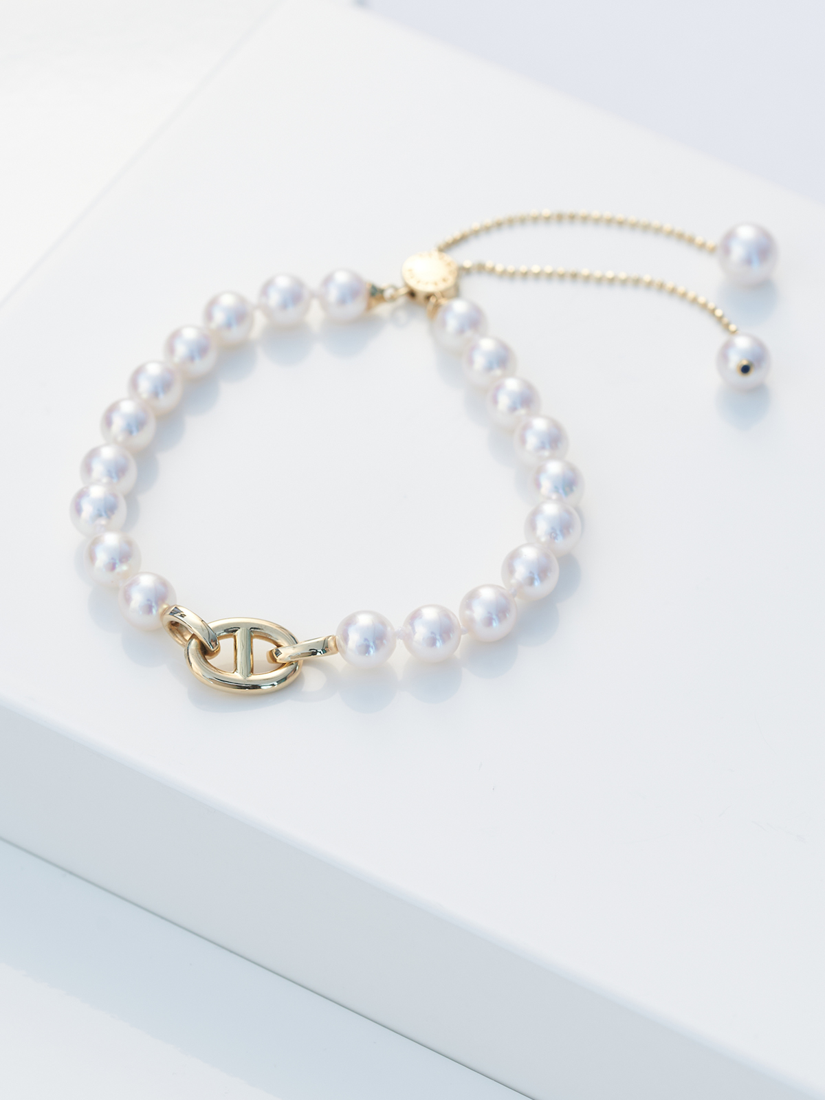 Akoya pearl bracelet with slide closure and anchor chain link detail in yellow gold
