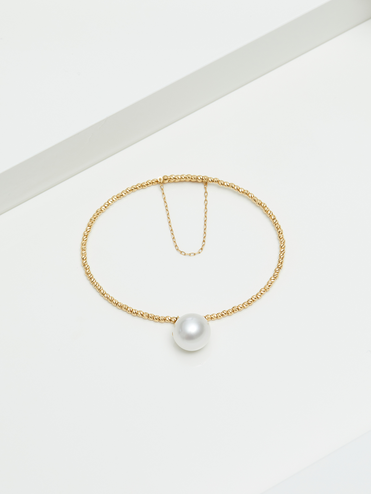 Eleganter Armreif mit einzelner Perle und Goldkettchen
